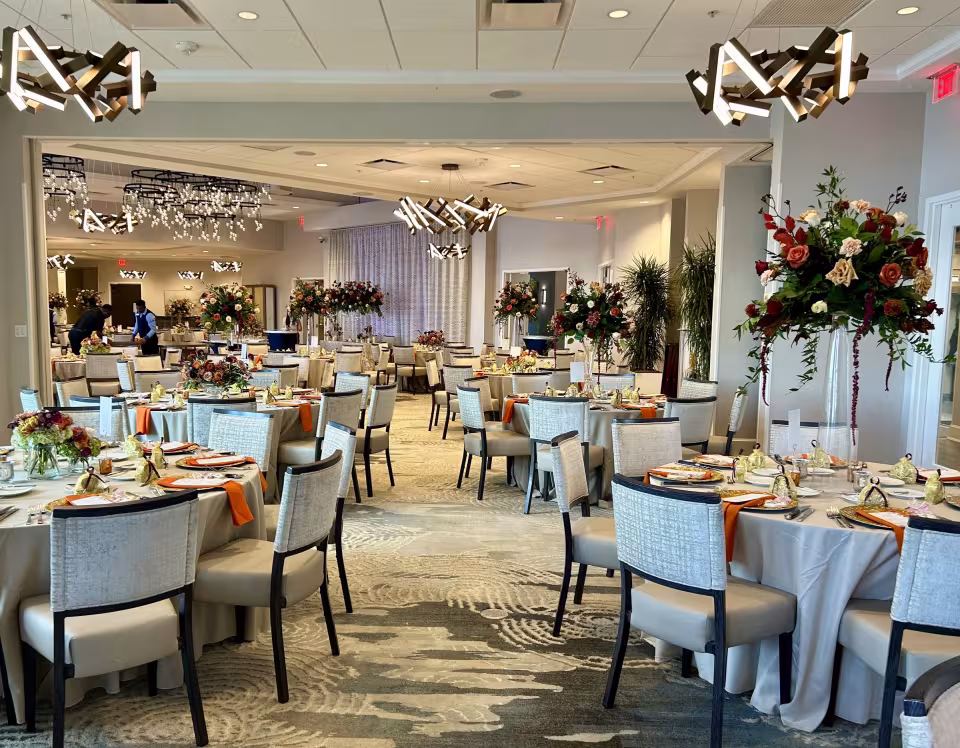 Indoor reception with tall autumn-toned arrangements and modern fixtures