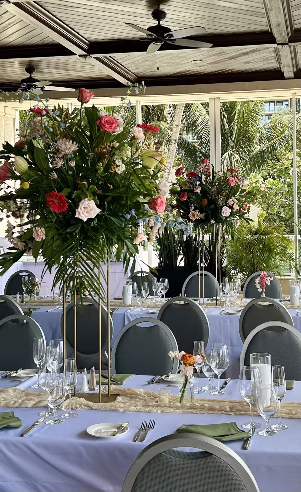 Tall pink and coral floral centerpieces on a long reception table